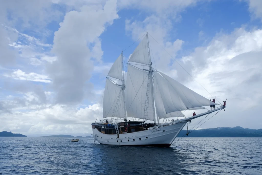 Jakare liveaboard at anchor in calm water off a limestone island in eastern Indonesia