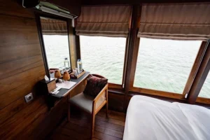 Sea-view desk and sleeping area in an upper-deck cabin aboard Nusa Kembara