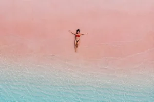 Aerial view of a woman relaxing on the pink sands of Pink Beach during a Lombok to Komodo boat trip 4 days 3 nights