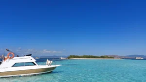The curved sandbar of Taka Makassar seen at water level with boats moored offshore