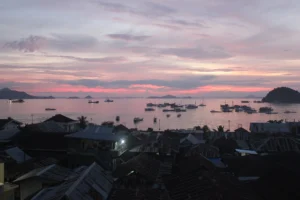 Pink sunset over Labuan Bajo bay with boats, seen from the hillside town