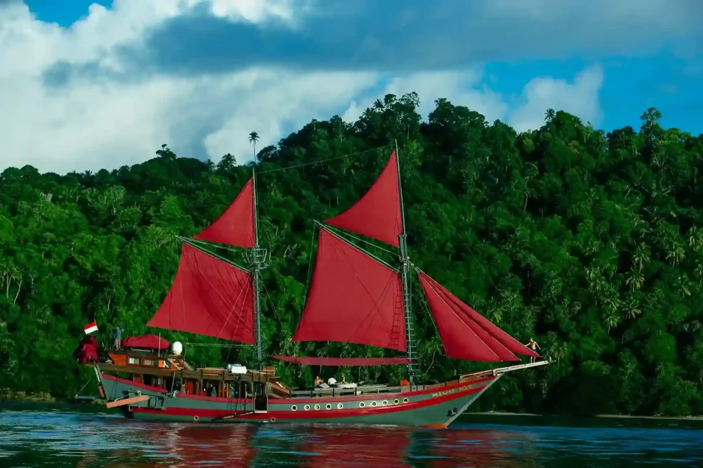 Side view of Manta Mae under its distinctive red sails